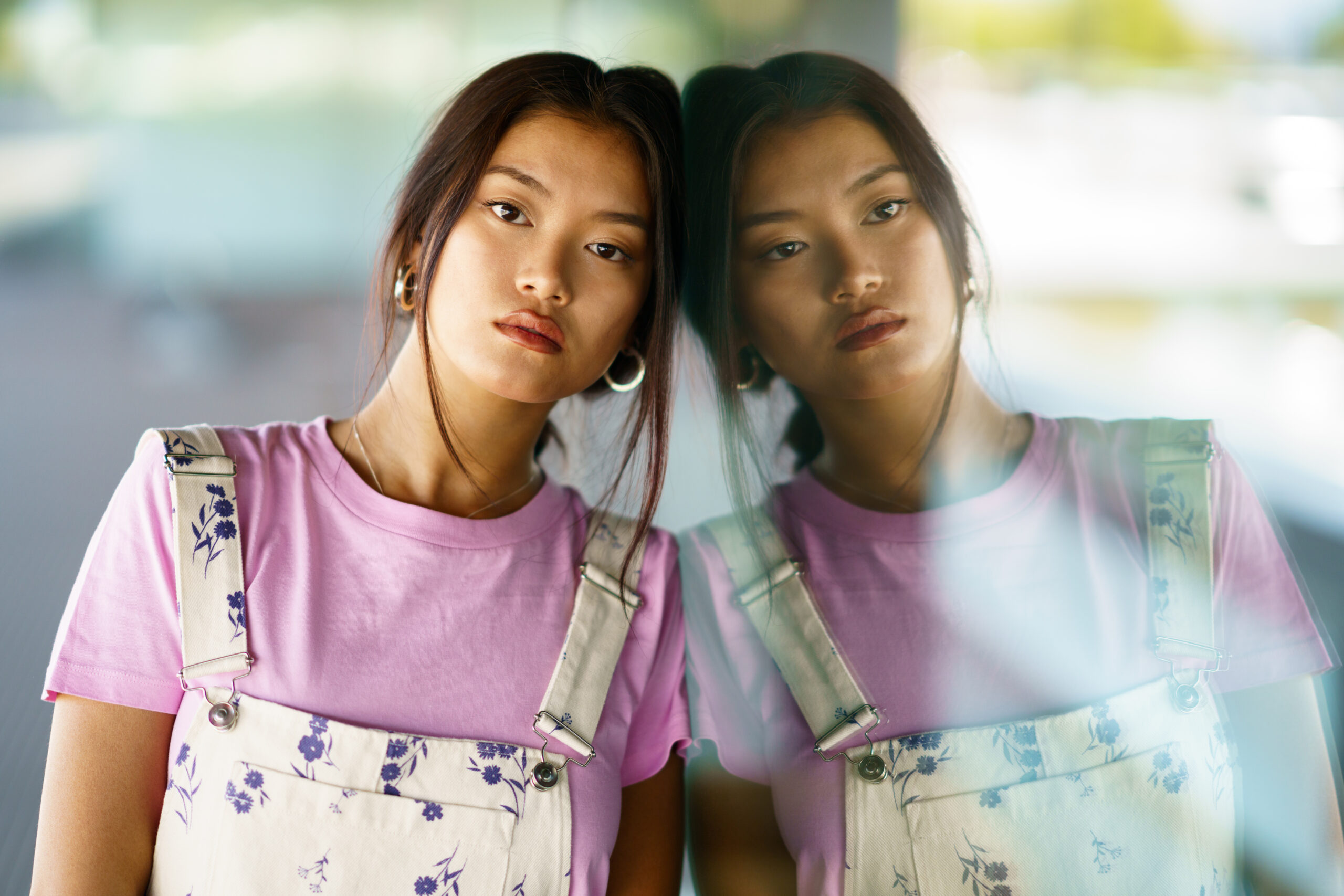 A woman looking at her own reflection, appearing troubled and searching.