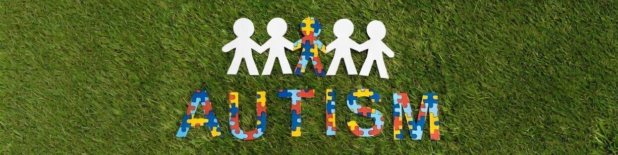 Autism awareness — multi-colored puzzle people figures on grass representing the autism spectrum