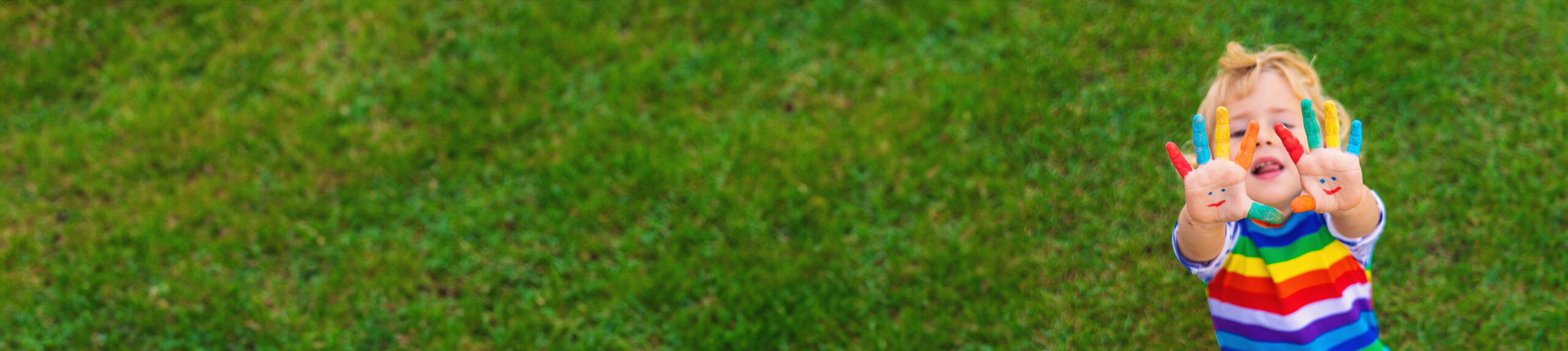 Joyful autistic child showing painted rainbow hands — autism support and family resources at Orchard Human Services