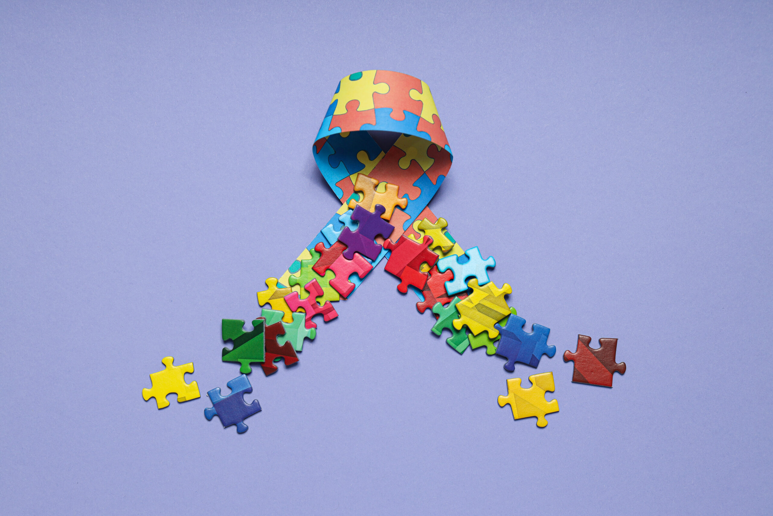 Autism awareness ribbon with multi-colored puzzle pieces representing the autism spectrum