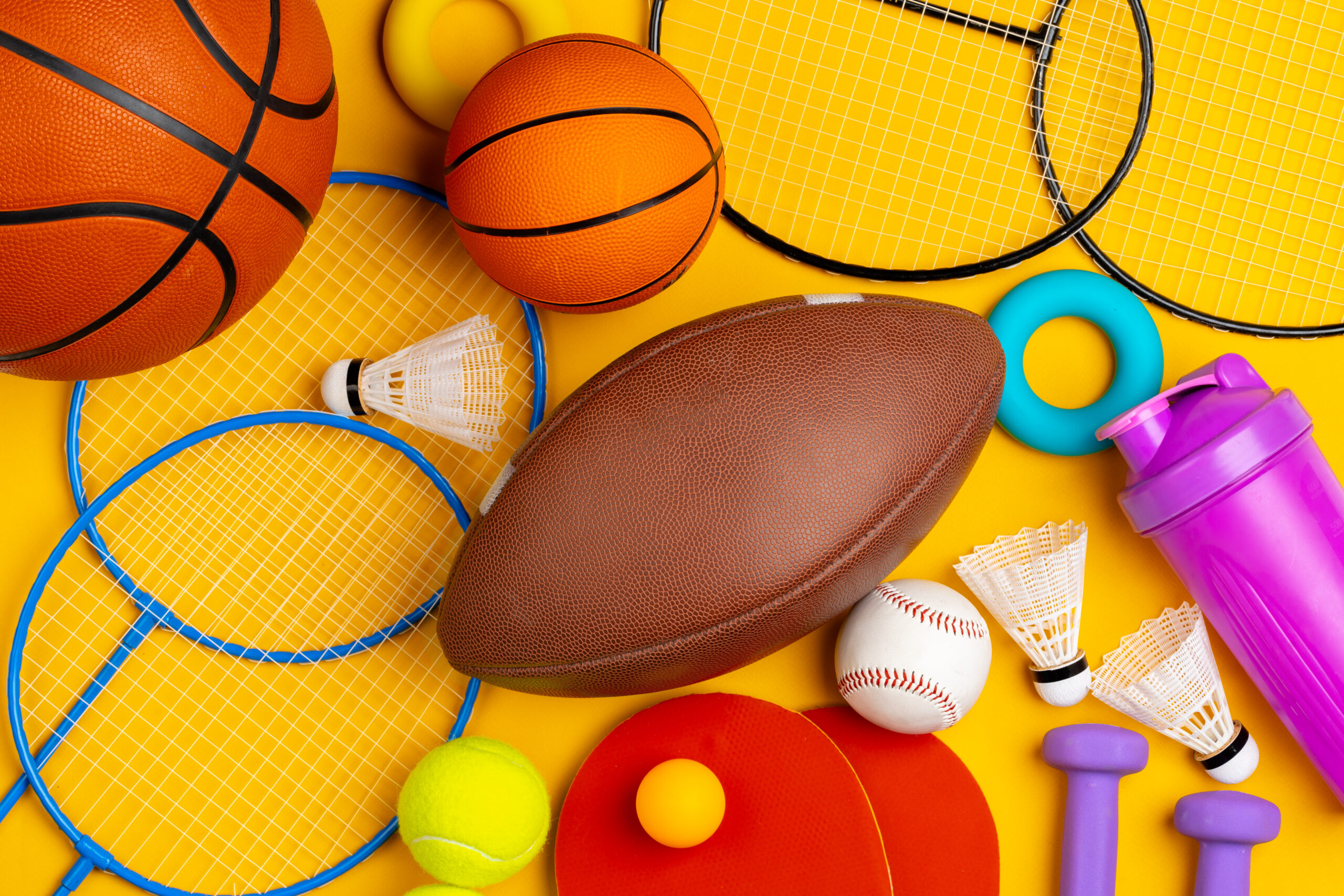 A variety of athletic equipment arranged on a yellow surface