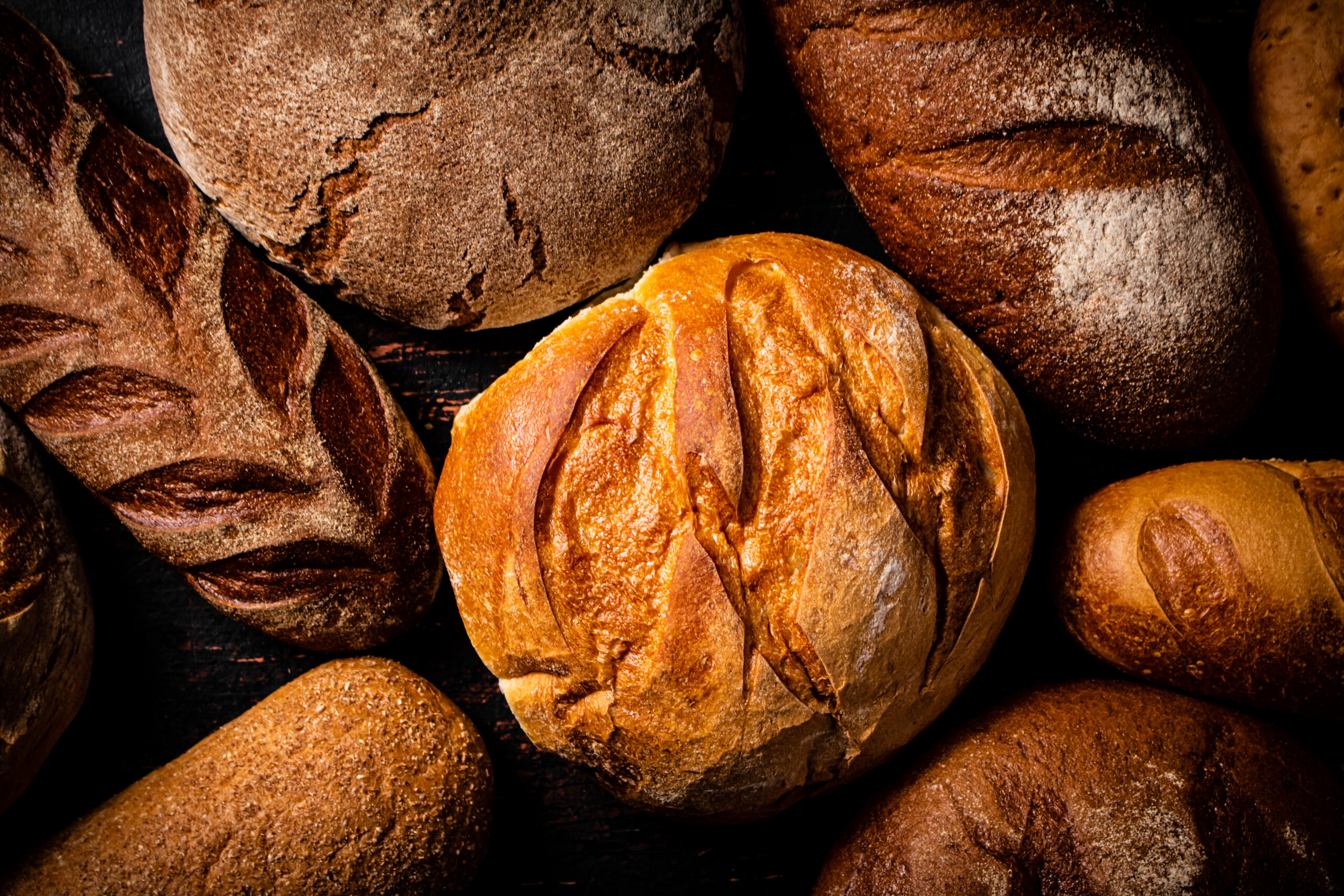 Artisan loaves of bread on a dark wooden surface.