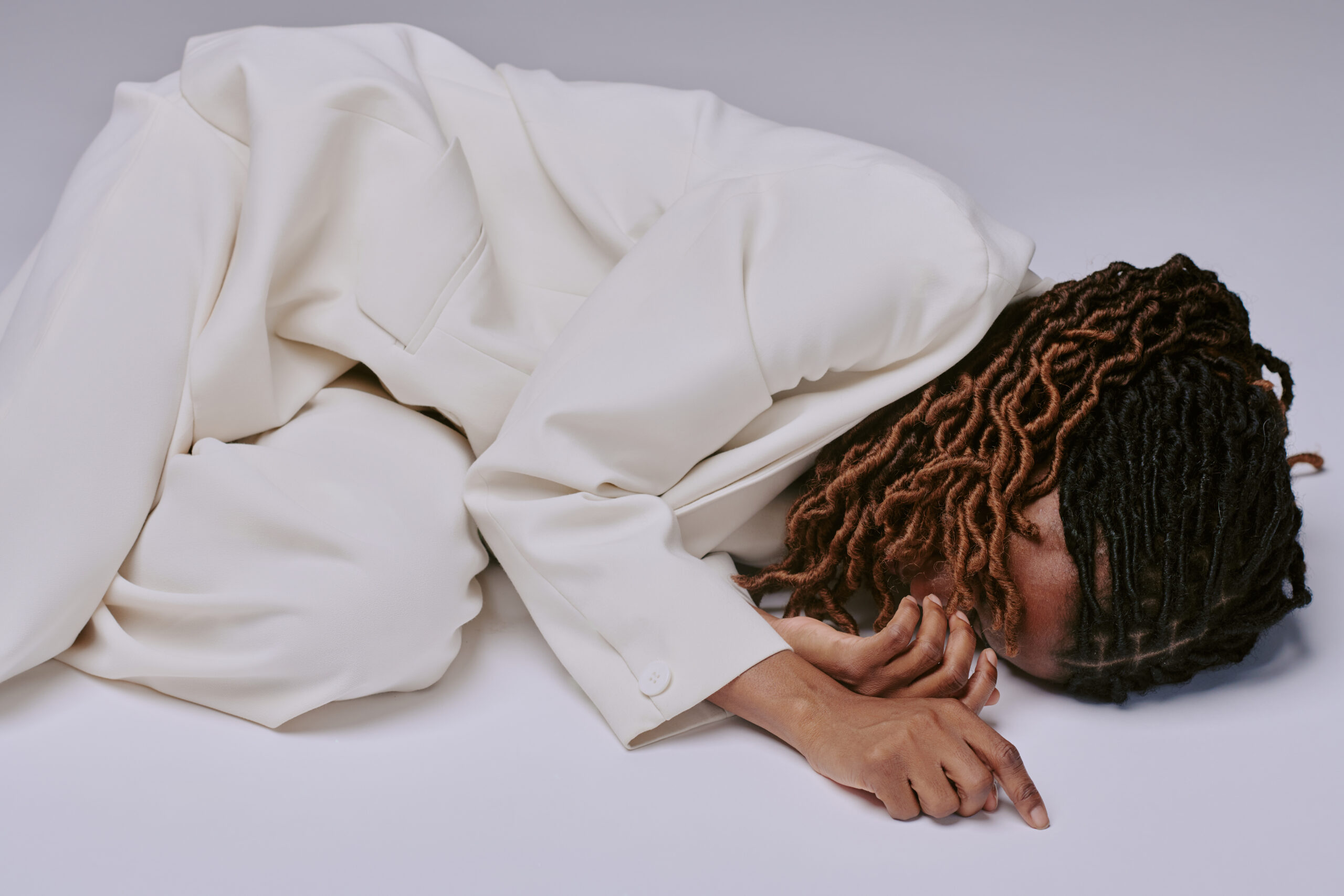 A person lying curled on the floor, conveying physical distress and exhaustion.