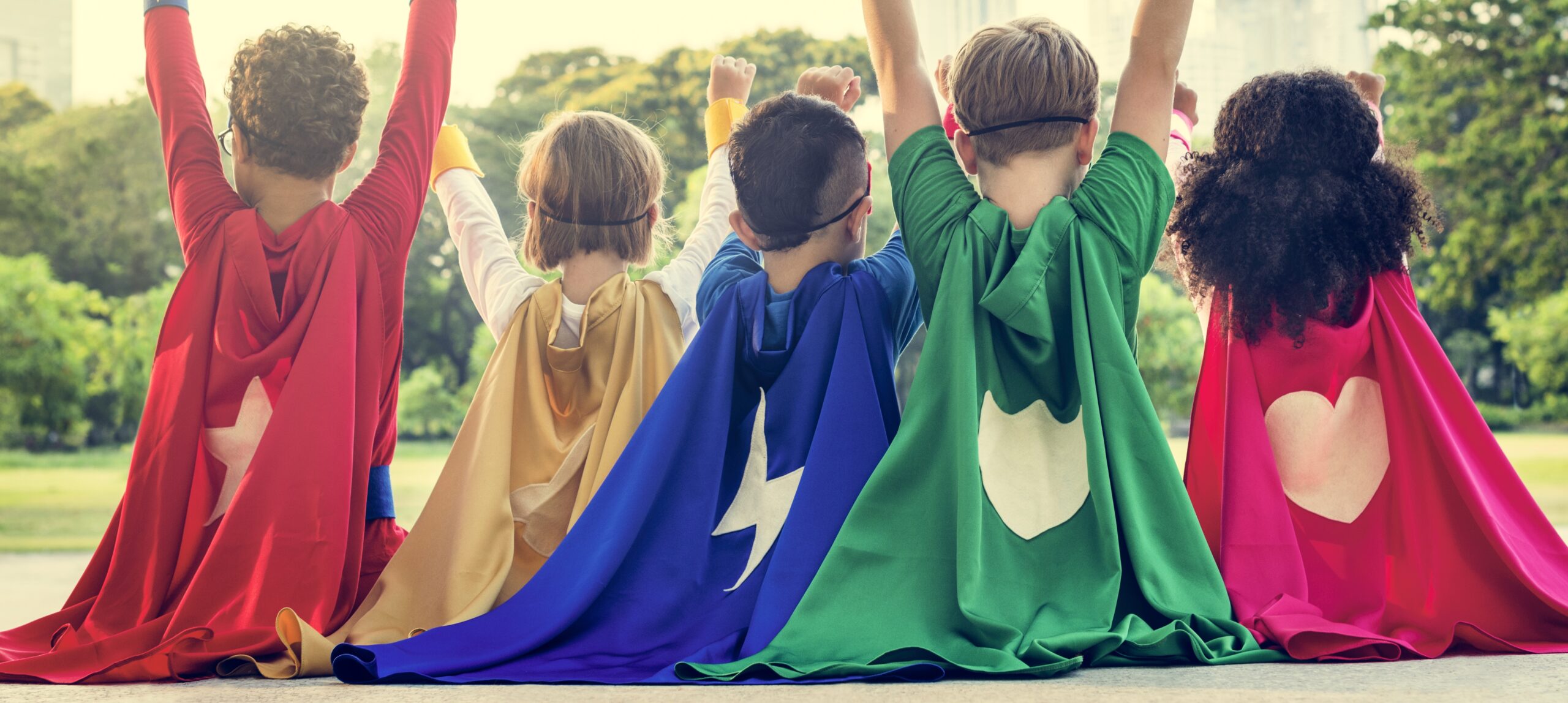 Children in superhero costumes with their arms raised